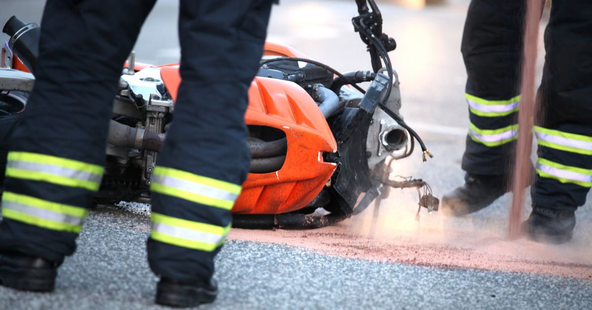 motorcycle on ground with firefighters standing near